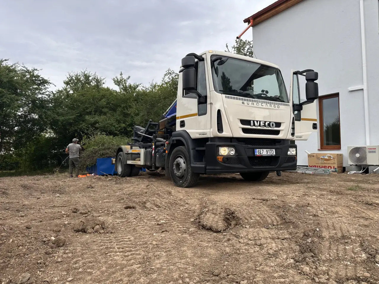 Kontejnerovka.cz Iveco on unpaved ground beside a family house
